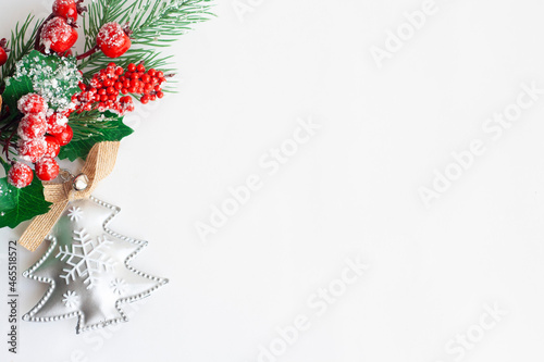Christmas tree twig with red berries and holly leaves and Christmas tree toy on a white background, copy space
