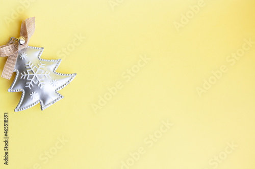 Silver Christmas tree toy with snowflake on yellow background, copy space