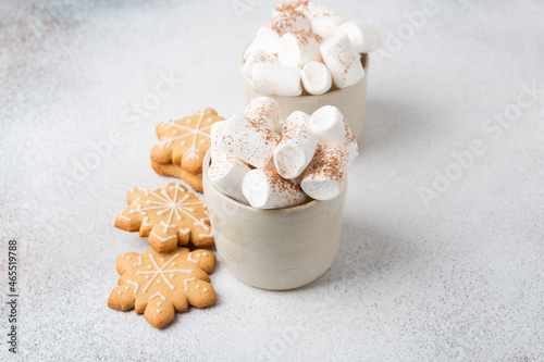 Two mugs of hot cocoa served with marshmallow on a gray background, copy space
