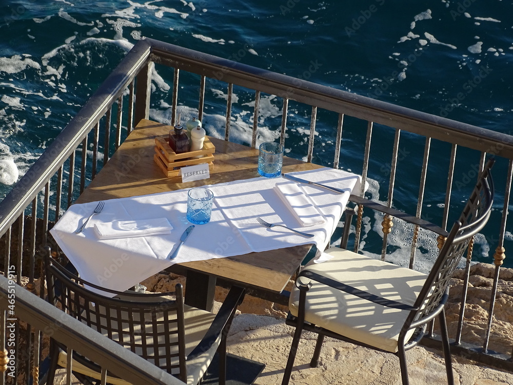 Fototapeta premium Gedeckter Tisch über dem Meer wartet auf seine Gäste