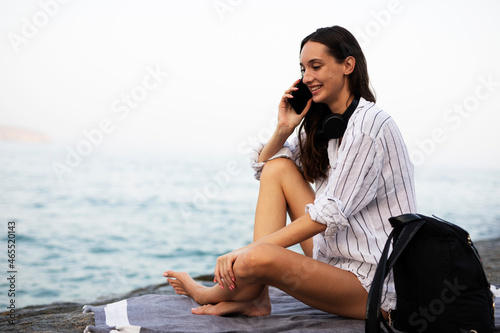 Happy young woman relaxing on the sandy beach. Beautiful woman talking to the phone