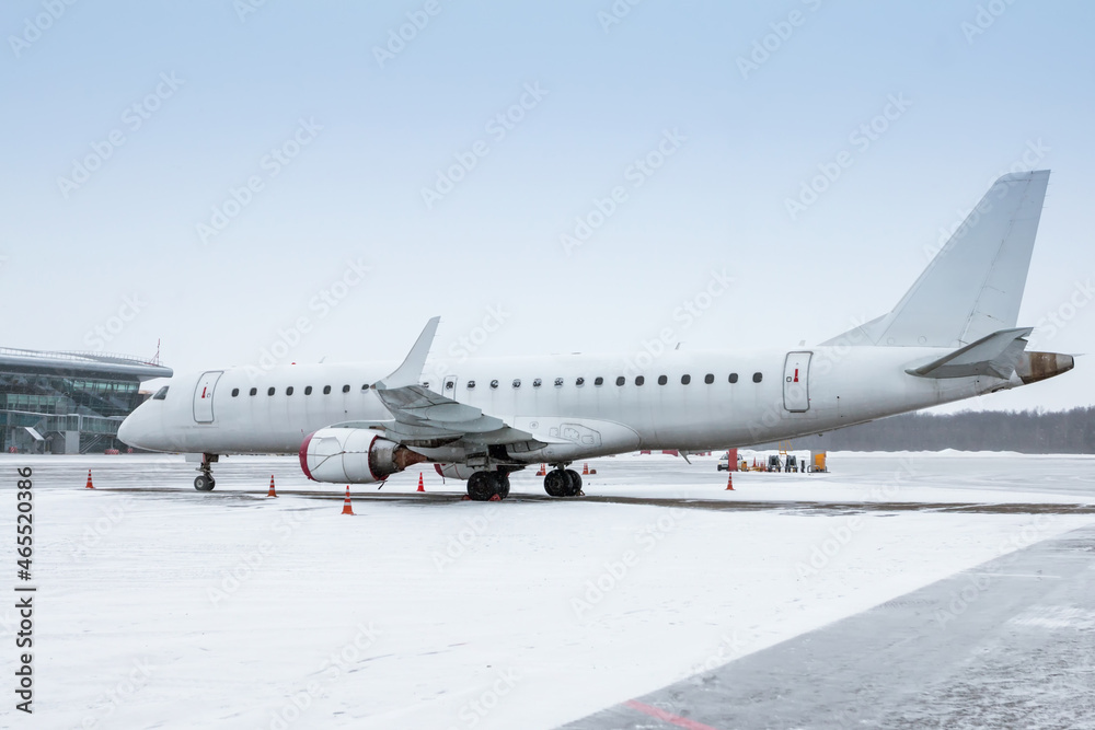 White passenger aircraft on the airport apron in a blizzard White passenger aircraft on the airport apron in a blizzard