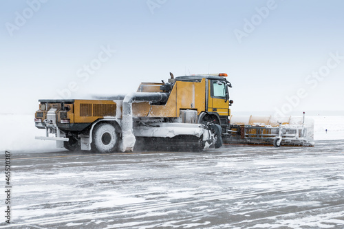 Snowplow truck cleans airport apron in a blizzard
