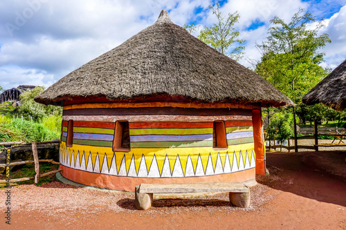 Traditional African house with colorful painted walls and a bench in front of the house photo