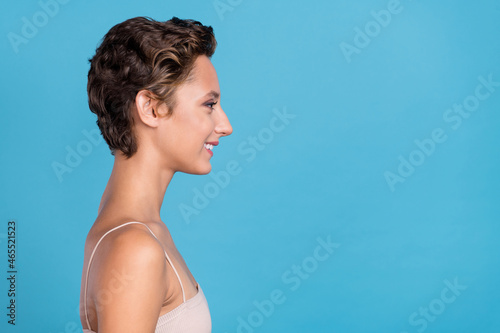 Photo of sweet pretty young woman dressed beige top looking empty space smiling isolated blue color background