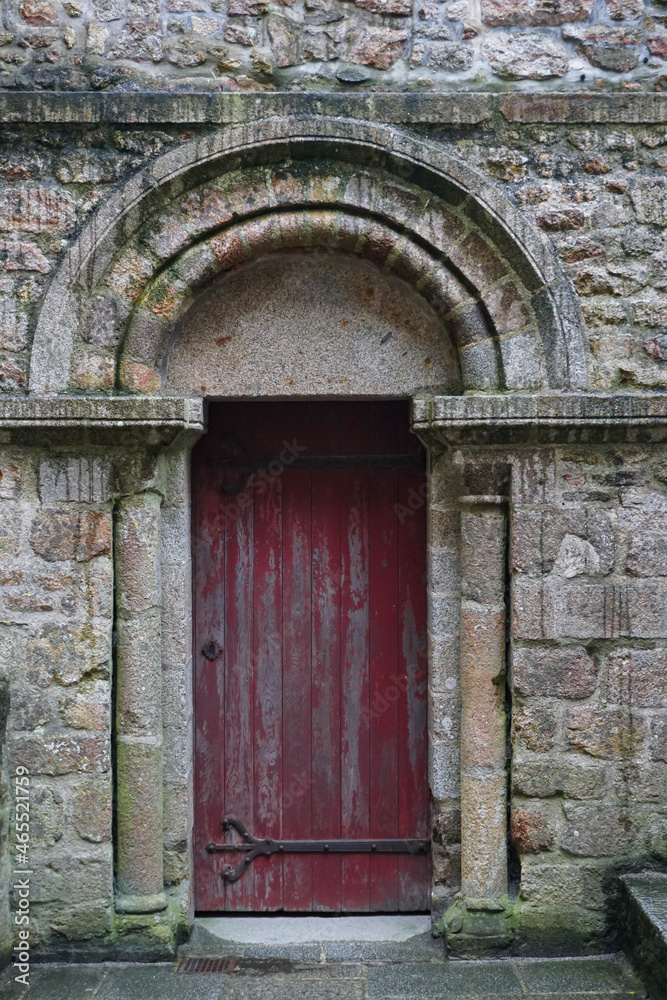Red painted antique door at the entrance of a castle with a beautiful dome carved in stone