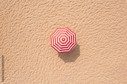 Striped beach umbrella on sandy coast, aerial view