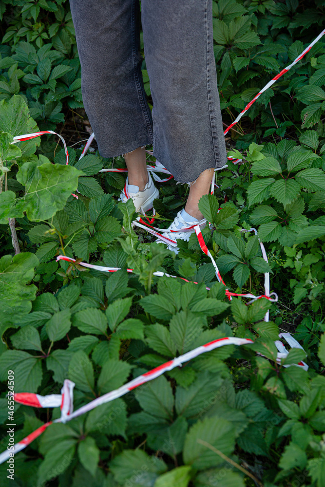 Fototapeta premium White young european girls legs standing within plants and restrictive tape