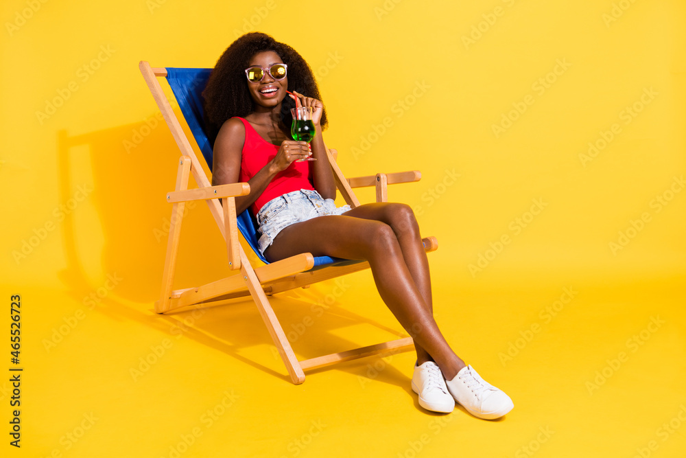Portrait of attractive cheerful girl sitting drinking juice relaxing day summertime isolated over bright yellow color background Portrait of attractive cheerful girl sitting drinking juice relaxing day summertime isolated over bright yellow color background