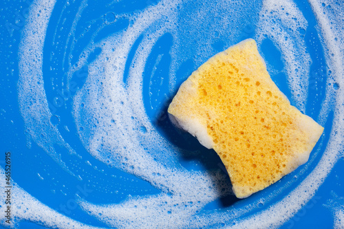 cleaning sponge wiping foam soap suds on blue background, household washing concept photo