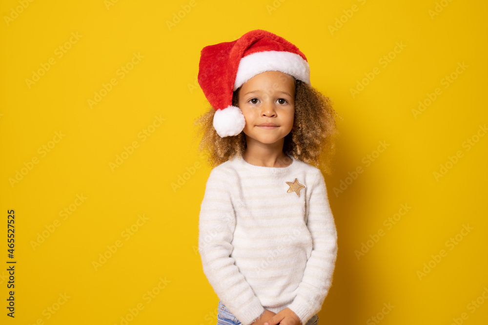 Cute little girl in santa claus hat isolated over yellow background. Cute little girl in santa claus hat isolated over yellow background.