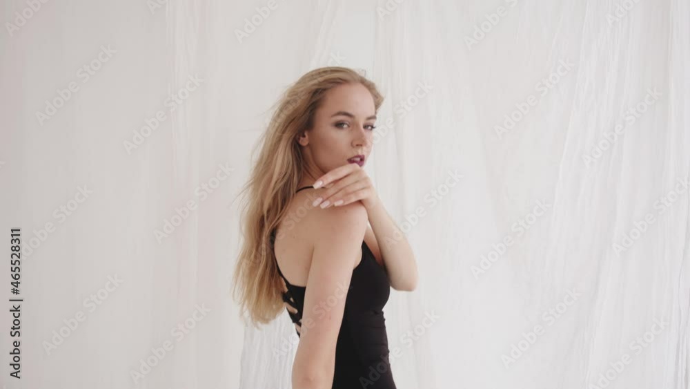 A young girl with bright makeup is engaged stretching in the studio and does a bend in a cloud of white tulle. Slow motion A young girl with bright makeup is engaged stretching in the studio and does a bend in a cloud of white tulle. Slow motion