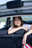 Dark blond slim young woman in open car trunk behind the seats