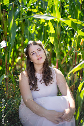 White young woman with long hair in light dress sitting in the tall grass