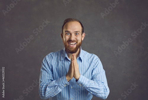 Emotional happy adult man joyfully claps his hands in a sign of finally achieved goal. Studio shot of a joyful man on a background of a gray wall. Concept of positive human emotions. Banner.
