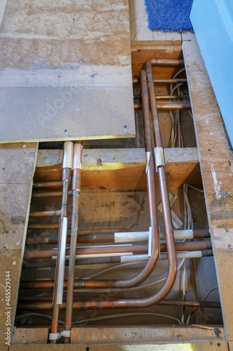 Close up of copper pipes under floor boards