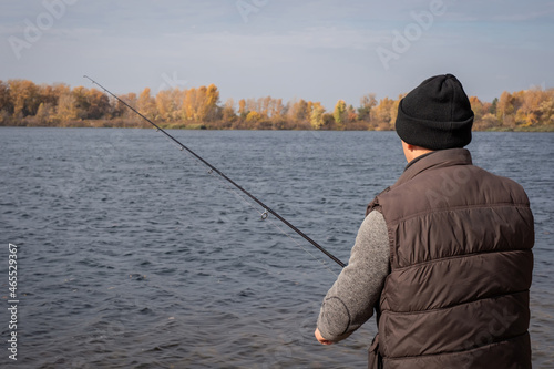 Fisherman with spinning on the river bank. A man with a fishing rod is fishing on the background of nature © Andrii