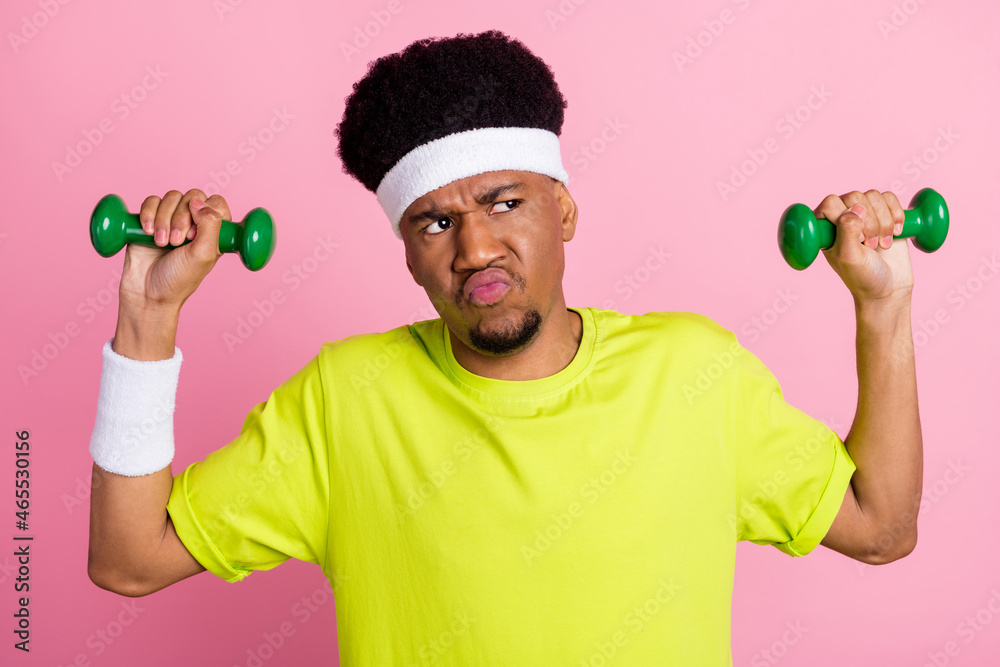 Photo of unhappy young dark skin man look empty space hold hands dumbbells isolated on pink color background Photo of unhappy young dark skin man look empty space hold hands dumbbells isolated on pink color background