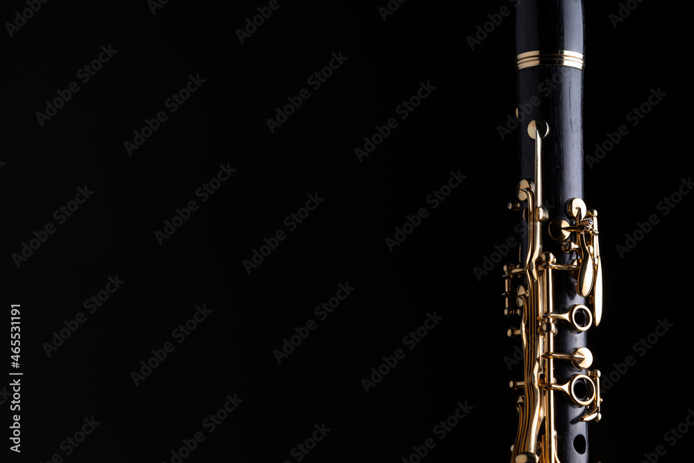 Naklejka premium Part of a clarinet with gold plated keys on a black background. A woodwind instrument common to classical music.