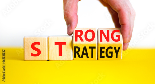 Strong strategy symbol. Businessman turns wooden cubes with words 'strong strategy'. Beautiful yellow table, white background, copy space. Business and strong strategy concept. photo