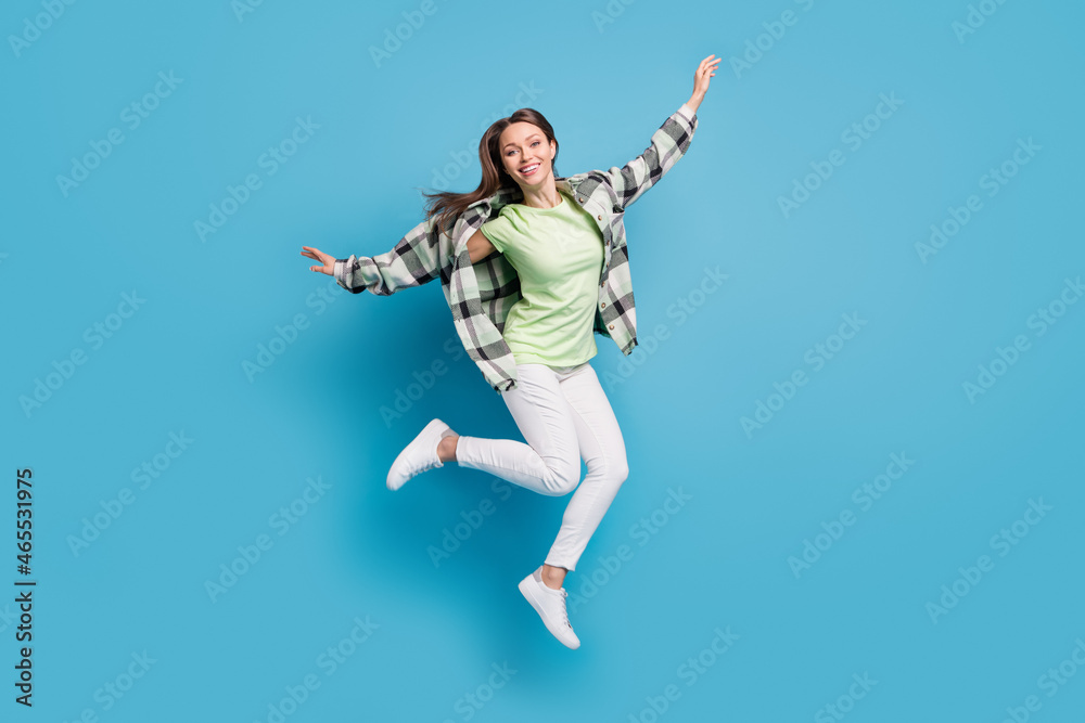 Full length profile side photo of young excited girl happy positive smile jump up air isolated over blue color background Full length profile side photo of young excited girl happy positive smile jump up air isolated over blue color background