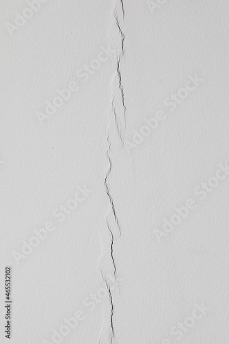 White cracked plaster. White surface with a crack. White cracked surface.