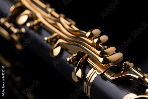 Photo Part of a clarinet with gold plated keys on a black background