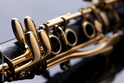 Slika na platnu Part of a clarinet with gold plated keys on a black background