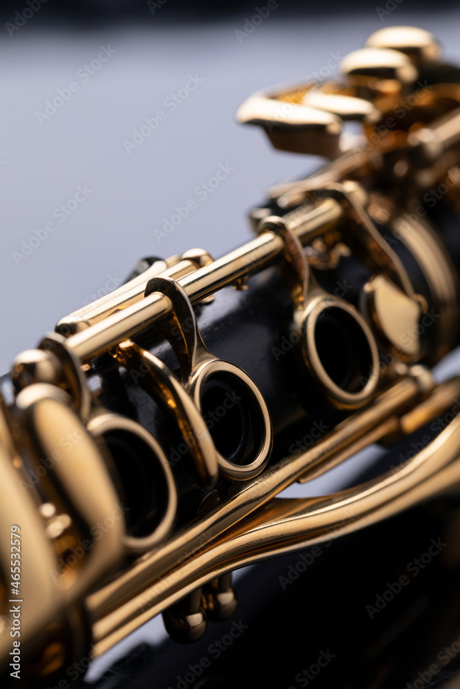 Naklejka premium Part of a clarinet with gold plated keys on a black background. A woodwind instrument common to classical music.