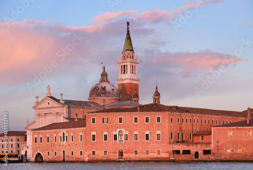 Romantic Venetian architecture at sunset. Church of San Giorgio Maggiore on San Giorgio island in Venice, Italy. Calm sea water and gorgeous orange and pink sunset clouds.