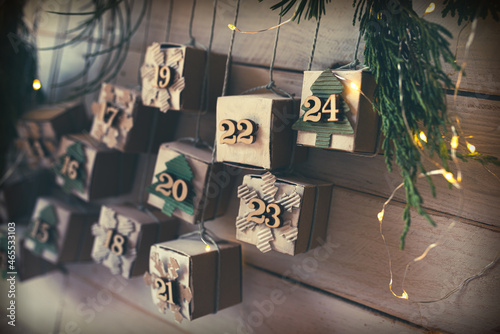 Homemade small carton boxes for advent surbrises with fairy light. Hanging vintage advent calendar made of cardboard for a environmentally conscious christmas. Close-up with short depth of field. photo