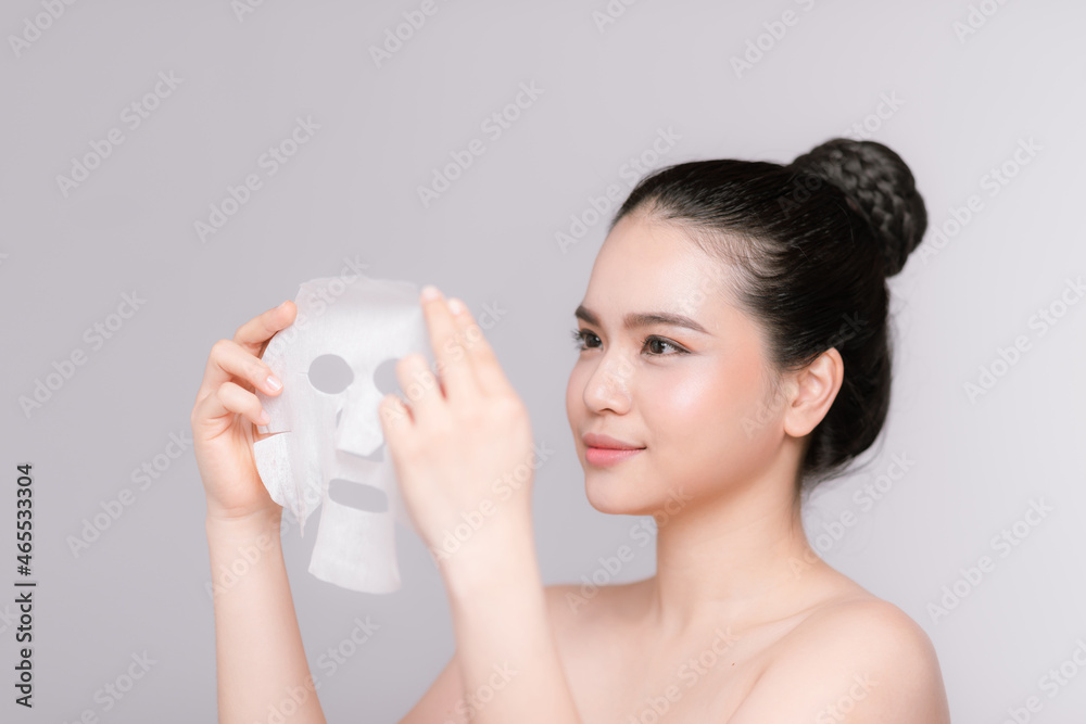 Beauty Skin Care Concept - Beautiful Caucasian Woman applying paper sheet mask on her face white background. Beauty Skin Care Concept - Beautiful Caucasian Woman applying paper sheet mask on her face white background.