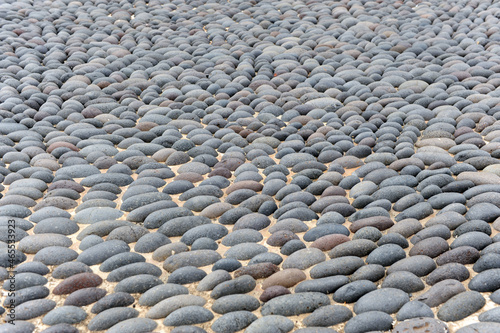 Pavimentación de una plaza con cantos rodados negros redondos. Superficie urbana pavimentada con piedras redondas negras . Pavimento tradicional de las Islas Canarias, España con piedras de lava negra