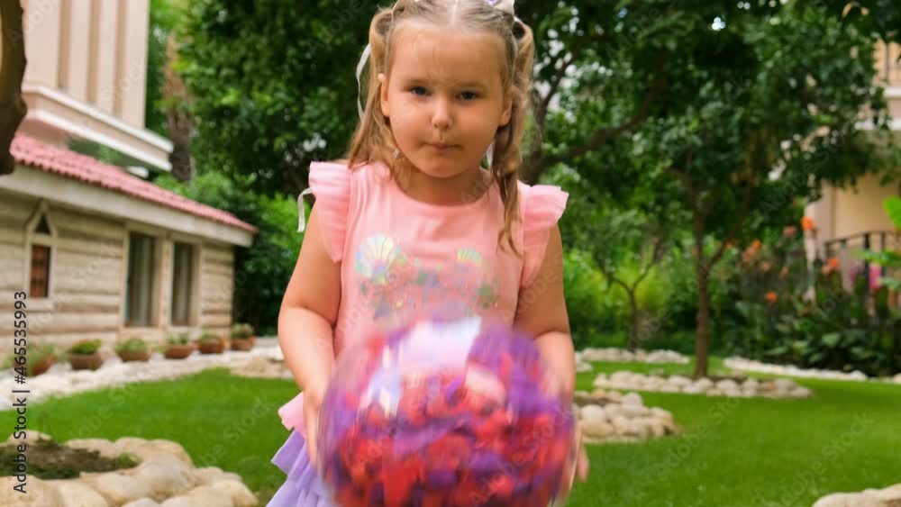 cute little girl, 3 years old, with two ponytails on her head, dressed in a delicate and multi-colored dress of pink blue color, plays with a bright transparent ball with multi-colored feathers inside cute little girl, 3 years old, with two ponytails on her head, dressed in a delicate and multi-colored dress of pink blue color, plays with a bright transparent ball with multi-colored feathers inside