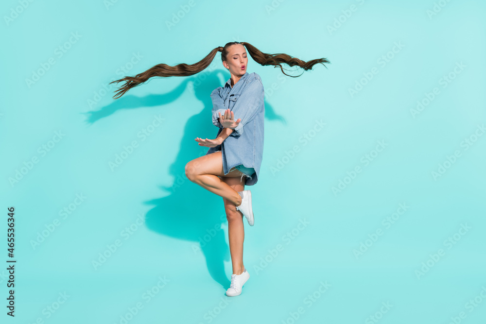 Photo of adorable shiny young lady wear jeans shirt smiling dancing isolated turquoise color background