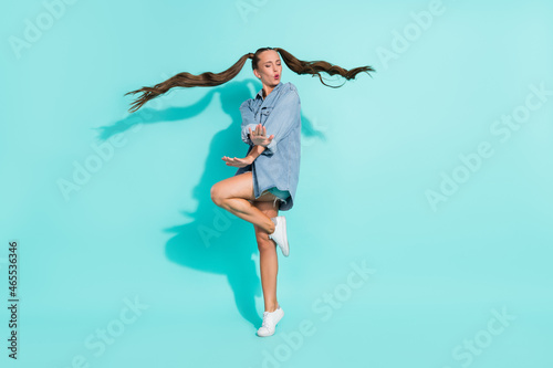 Photo of adorable shiny young lady wear jeans shirt smiling dancing isolated turquoise color background © deagreez