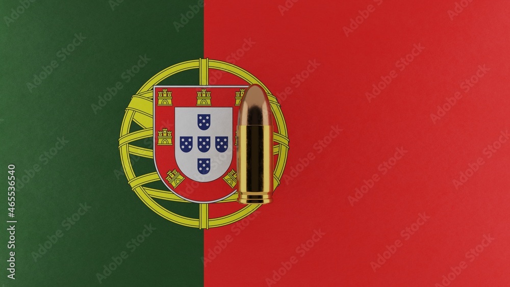 Top down view of a 9mm bullet in the center and on top of the flag of Portugal Top down view of a 9mm bullet in the center and on top of the flag of Portugal