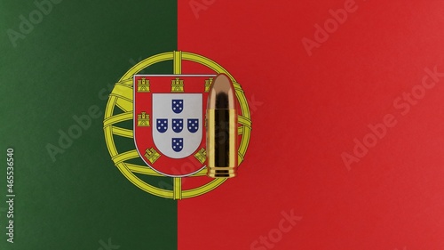 Top down view of a 9mm bullet in the center and on top of the flag of Portugal