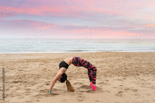 Athletic fitness woman practicing wheel pose , chakrasana or urdhva dhanurasana.Female wearing sportswear working out, at the beach,outdoors lifestyle fitness exercises training concept photo
