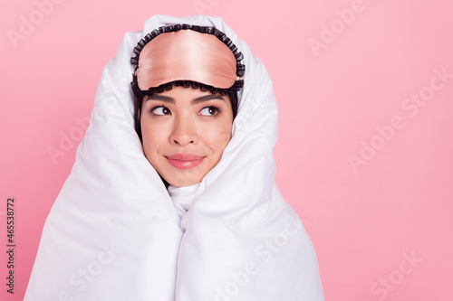Photo of shiny adorable woman nightwear mask smiling rolling duvet looking empty space isolated pink color background