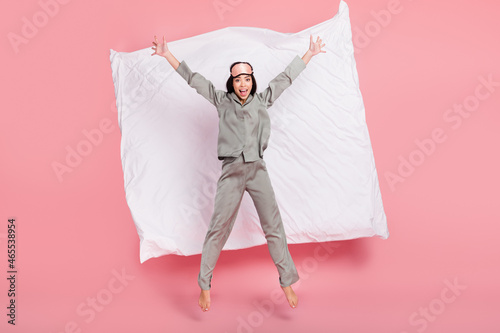 Full length photo of sweet funny lady sleepwear mask jumping high like star smiling isolated pink color background