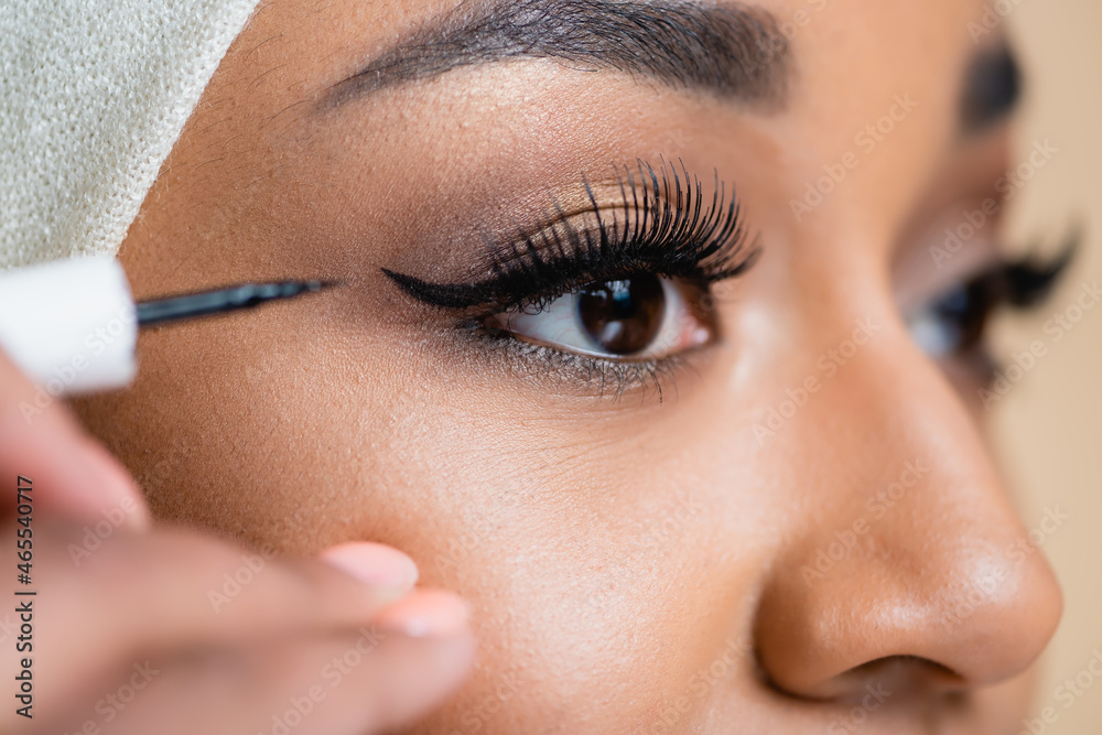 close up of young arabian woman applying black eye liner
