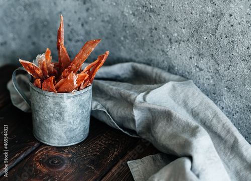 Dried chicken, dried poultry, cut into strips in a metal bucket on a wooden background. High quality photo