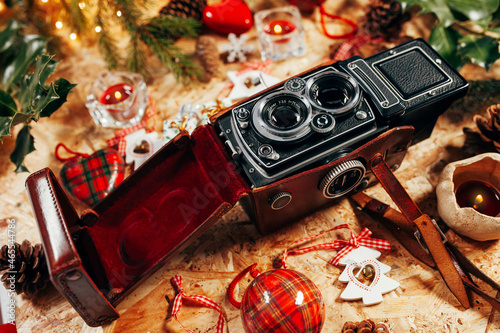 Christmas decorations, vintage medium format compact camera, tree branch, led lights, gifts on wooden background. Christmas, new year, winter concept. Flat lay, top view, copy space. photo