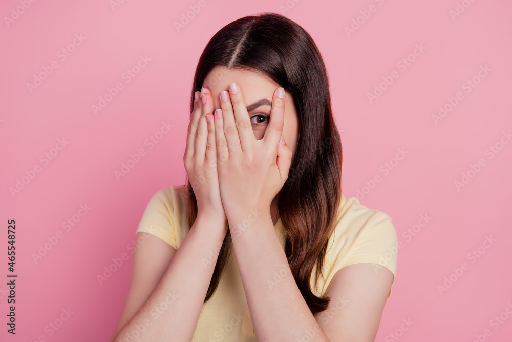 Photo of scared worried nervous lady arms cover face peek eyes look camera on pink background Photo of scared worried nervous lady arms cover face peek eyes look camera on pink background