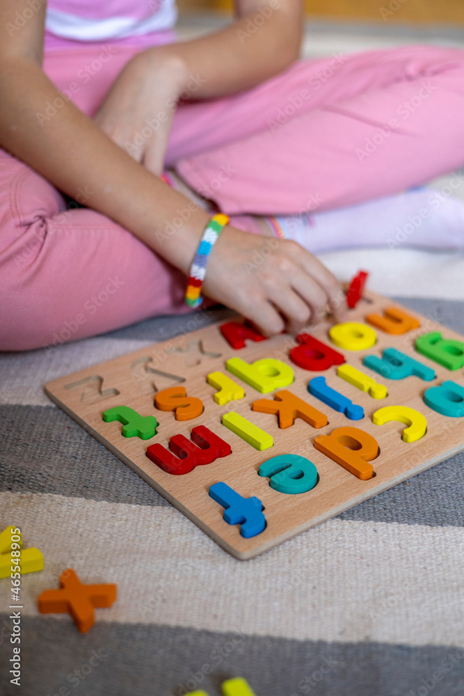 Fototapeta premium Child learns to put words out of letters. English alphabet. Eco friendly toy