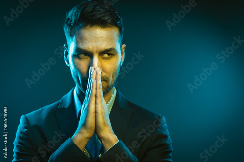  Serious Business Man Has an Idea How to Improve His Business. Strong White Man With Folded Hands in Creative Neon Light. Close-Up Portrait on Blue Background. High quality photo