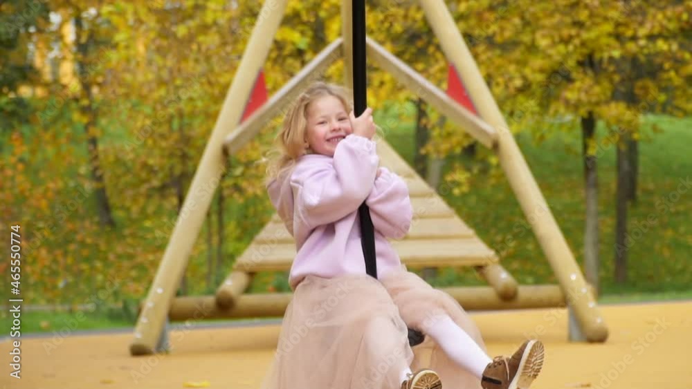 Happy child is riding swing. Look in camera laugh. girl flies on bungee. Cheerful childhood. Walk in park at new playground for children. apartment complex. fairy tale for life. fun Princess in autumn Happy child is riding swing. Look in camera laugh. girl flies on bungee. Cheerful childhood. Walk in park at new playground for children. apartment complex. fairy tale for life. fun Princess in autumn