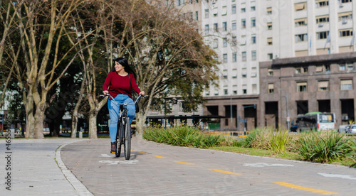young latina business woman riding her bicycle on the bike path smiling © juanpablo