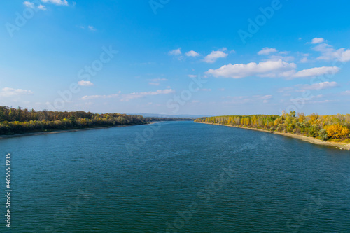 Beautiful autumn scenery. The blue Danube and the forest in the colors of autumn.